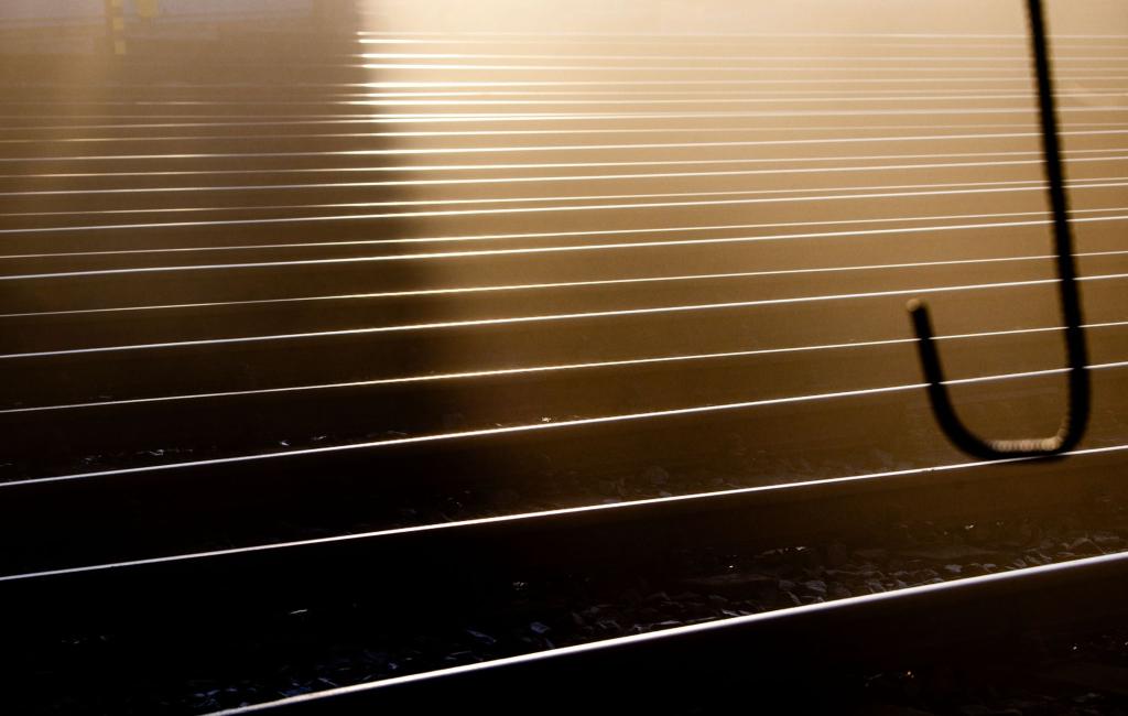 Wie ein abstraktes Gemälde: Schienen im Güterbahnhof von Wismar reflektieren das Licht der aufgehenden Sonne. - Foto: Jens Büttner/dpa