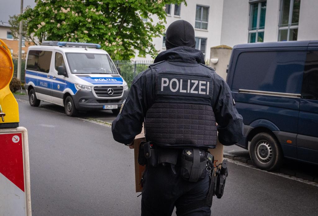 Ein Polizist trägt bei einem Einsatz in Bonn einen Karton mit beschlagnahmtem Material aus einem Gebäude. - Foto: Benjamin Westhoff/dpa