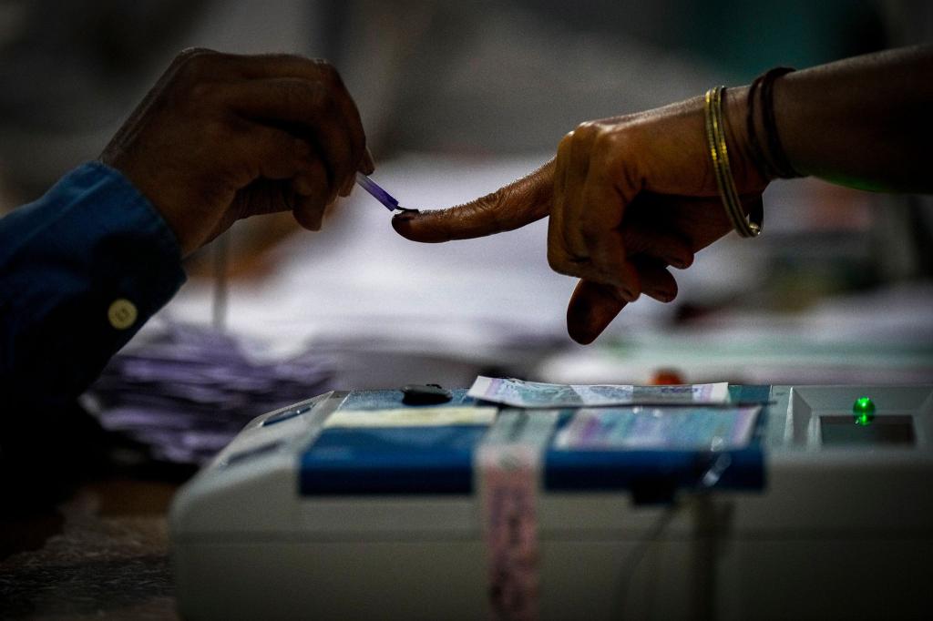 Ein Wahlhelfer markiert den Zeigefinger einer Frau mit unauslöschlicher Tinte, als sie während der indischen Parlamentswahlen im Dorf Bahona im nordöstlichen Assam zur Stimmabgabe erscheint. - Foto: Anupam Nath/AP