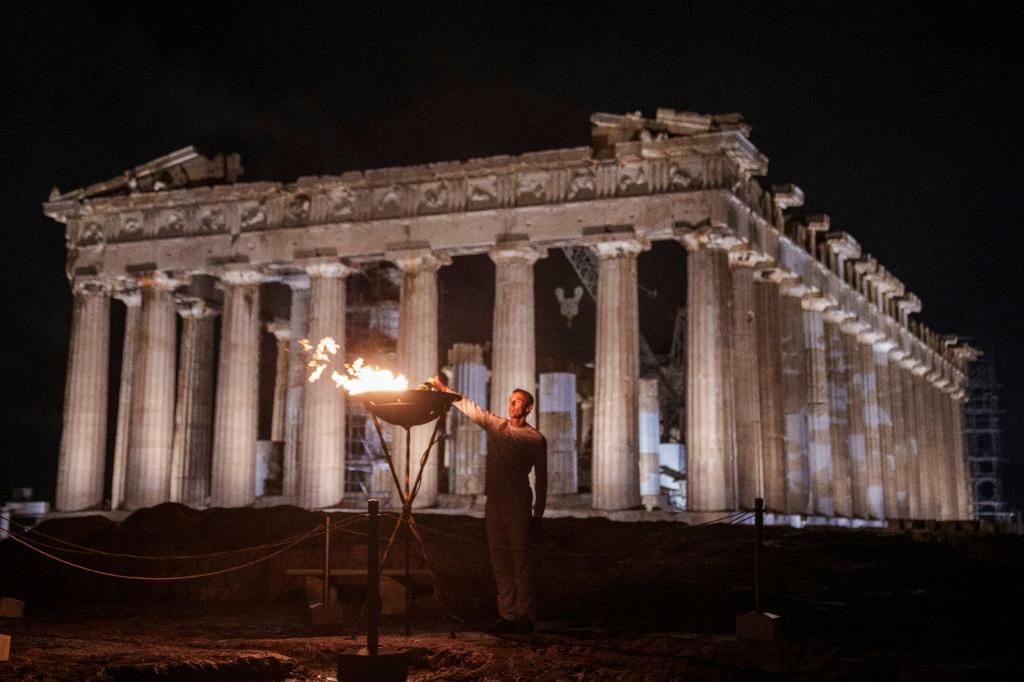 Ein Kessel mit dem olympischen Feuer wird vor dem Parthenon auf dem Akropolis-Hügel in Athen entzündet. - Foto: Petros Giannakouris/AP /dpa