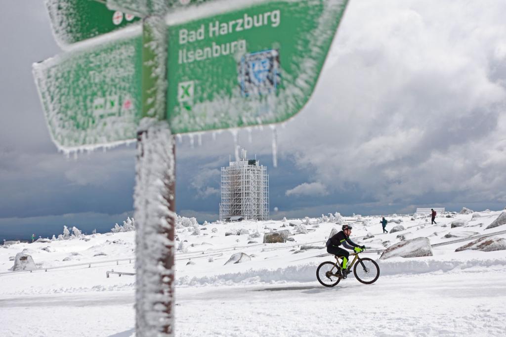 Ein Radfahrer ist auf dem schneebedeckten Brocken unterwegs. - Foto: Matthias Bein/dpa