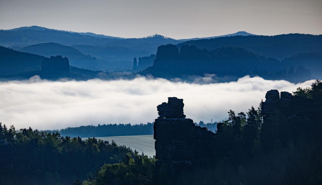 Nebel zieht am Morgen in der Sächsischen Schweiz zwischen Felsen entlang. - Foto: Robert Michael/dpa
