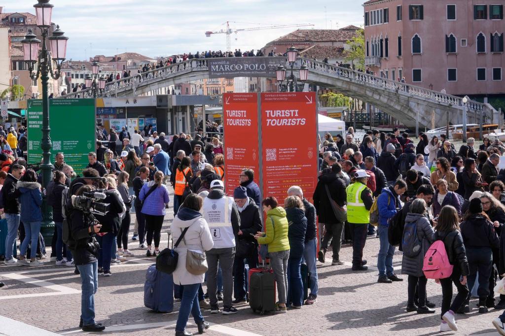 Vor dem Hauptbahnhof überprüfen Kontrolleure den QR-Code der Touristen, mit dem die Zahlung nachgewiesen wird. - Foto: Luca Bruno/AP/dpa
