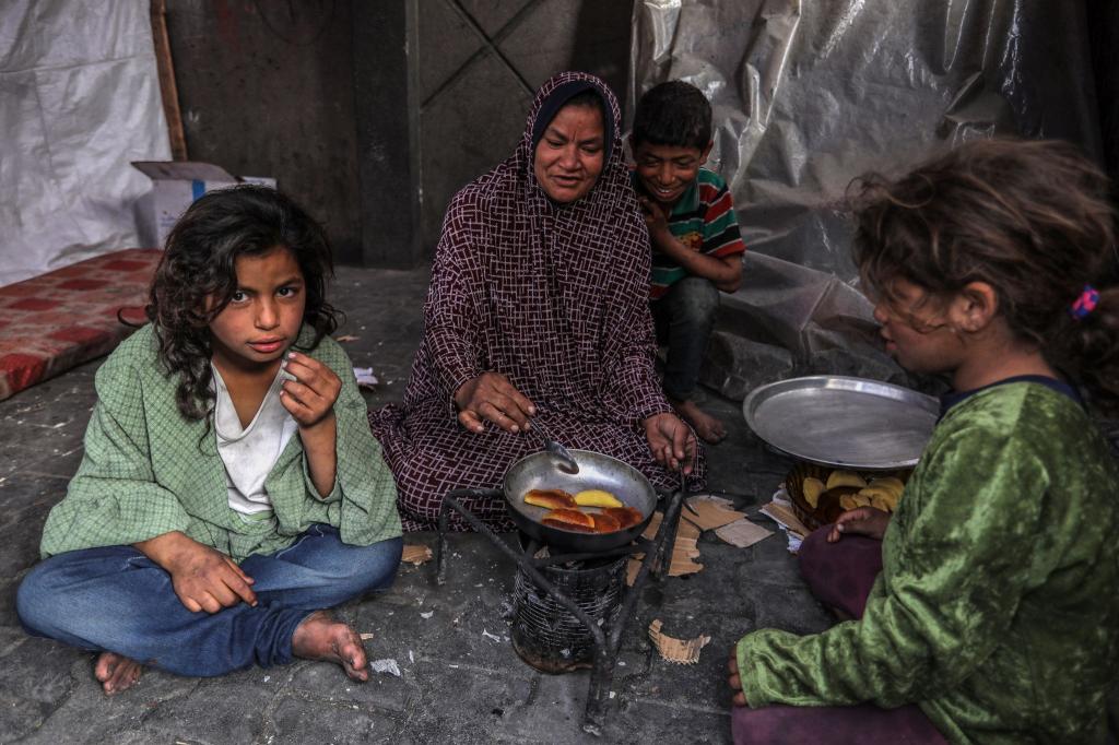 Eine palästinensische Familie kocht in einem behelfsmäßigen Zelt in Rafah. - Foto: Abed Rahim Khatib/dpa