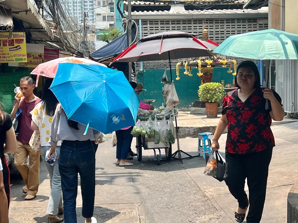 Menschen schützen sich in Bangkok mit Schirmen vor der extremen Hitze und vor der Sonne. Nicht nur in Thailand, sondern auch auf den Philippinen leiden die Menschen derzeit unter den hohen Temperaturen. - Foto: Carola Frentzen/dpa