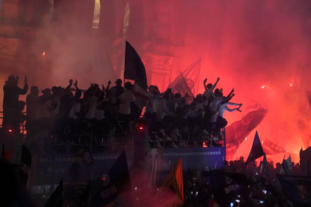 Tausende von Fans jubeln und zünden Feuerwerkskörper, als ein Bus die triumphierenden Spieler von Inter Mailand, die ihren 20. Titel in der italienischen Serie A feiern, vor den gotischen Dom von Mailand bringt. - Foto: Luca Bruno/AP/dpa