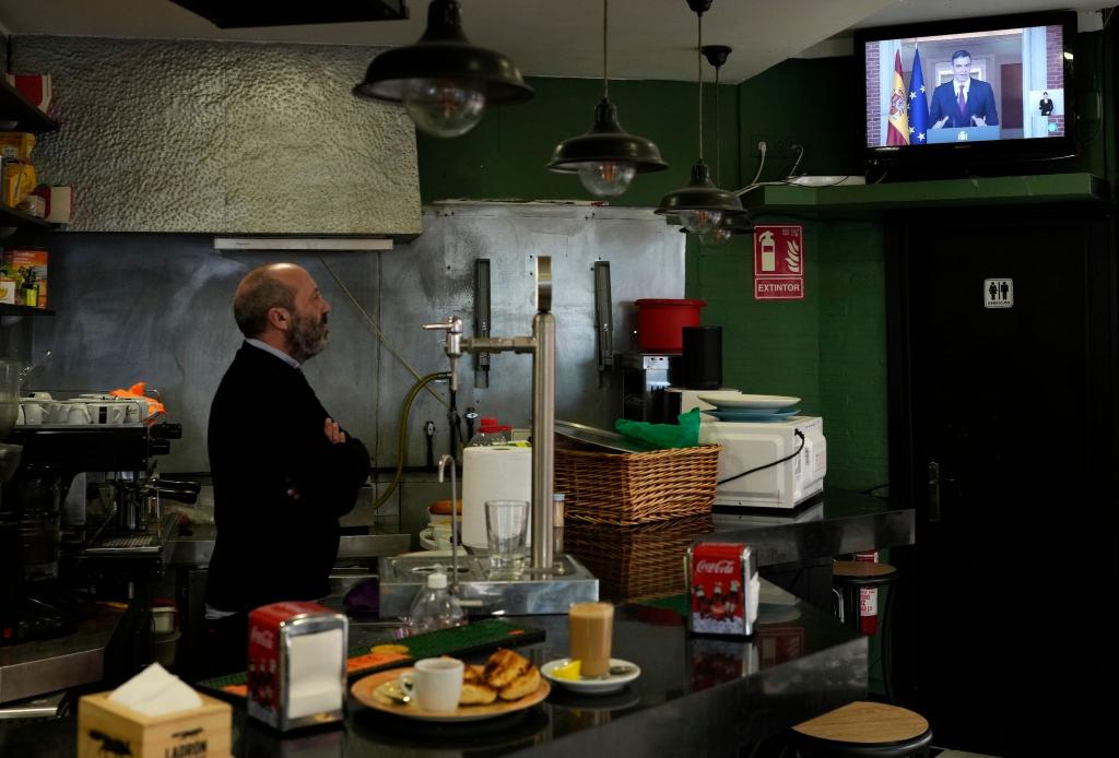 Ein Barkeeper beobachtet, wie der spanische Ministerpräsident Pedro Sánchez eine Fernsehansprache hält. - Foto: Bernat Armangue/AP/dpa