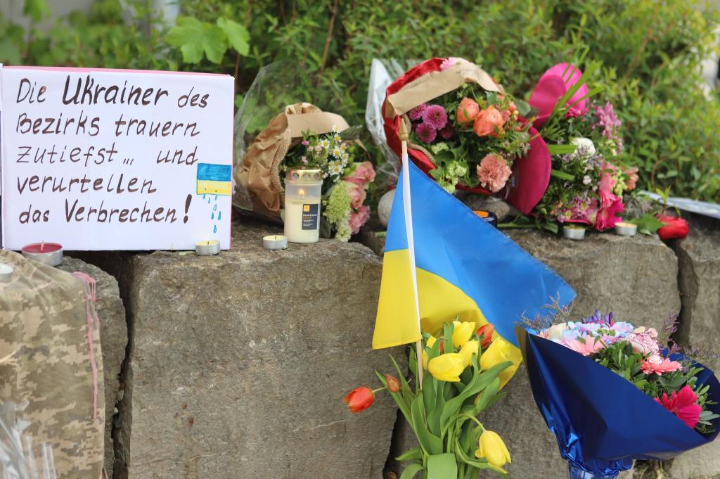 Am Gelände eines Einkaufszentrums, an dem zwei Männer aus der Ukraine getötet worden sind, wurden Blumen niedergelegt sowie eine kleine ukrainische Flagge aufgestellt. - Foto: Constanze Wilz/dpa