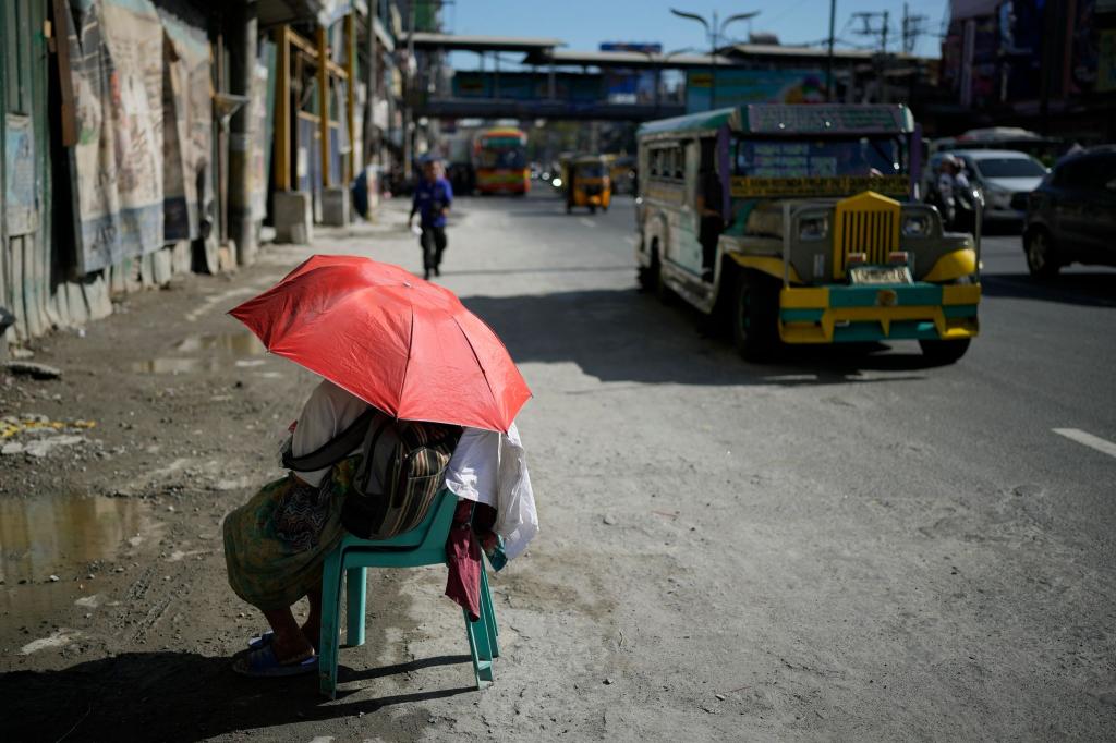 Extreme Hitze in den Straßen von Manila: Eine Verkäuferin schützt sich mit einem Regenschirm vor der Sonne. Auf den Philippinen und in weiteren südostasiatischen Ländern herrschen Rekordtemperaturen von gefühlt über 50 Grad. - Foto: Aaron Favila/AP/dpa