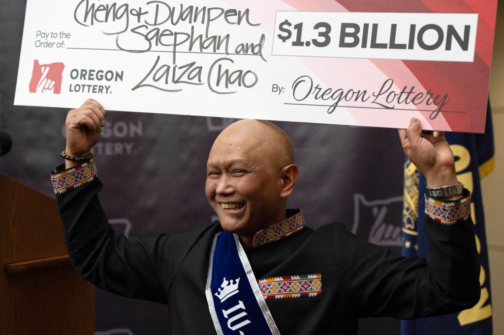 Cheng Saephan hält einen Riesencheck in Höhe von 1,3 Milliarden Dollar in die Höhe. - Foto: Jenny Kane/AP/dpa