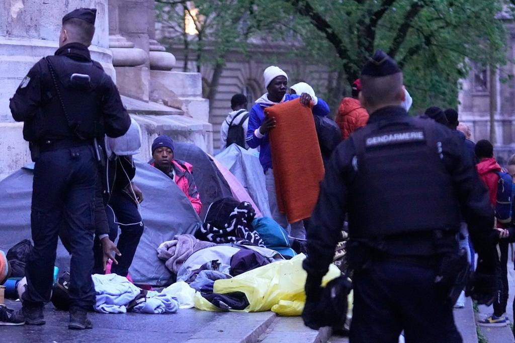 Polizisten vertreiben Migranten aus einem behelfsmäßigen Lager in Paris. Ähnliche Aktionen werden von den Polizeibehörden in den Monaten vor den Olympischen Spielen täglich durchgeführt. - Foto: Michel Euler/AP