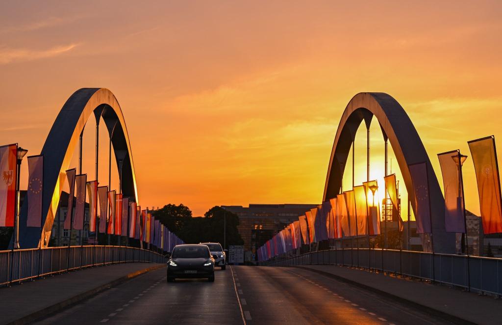 Autos fahren zum Sonnenaufgang über die Stadtbrücke über den Grenzfluss Oder zwischen Frankfurt und dem polnischen Slubice. Zum 20. Jahrestag des EU-Beitritts Polens wollen sich am Mittag die Außenminister der beiden Nachbarländer treffen. - Foto: Patrick Pleul/dpa
