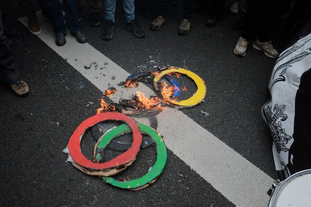 Mit brennenden Ringen machen einige Pariser am 1. Mai darauf aufmerksam, was sie wirklich von der Ausrichtung der Olympischen Spiele in ihrer Stadt halten. - Foto: Joao Daniel Pereira/ZUMA Press Wire/dpa