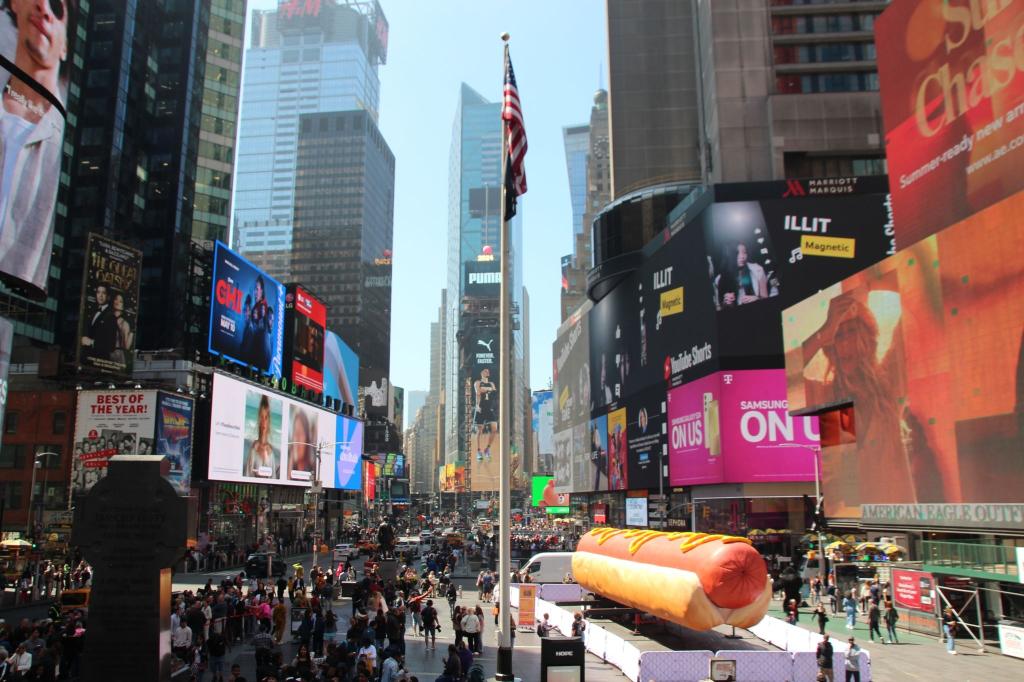Guten Appetit: Mitten auf dem New Yorker Times Square steht jetzt ein Riesen-Hotdog. Das Kunstwerk des US-Duos Jen Catron und Paul Outlaw entwickelte sich schon kurz nach dem Aufstellen zum Magnet für Selfies Dutzender Menschen. - Foto: Christina Horsten/dpa