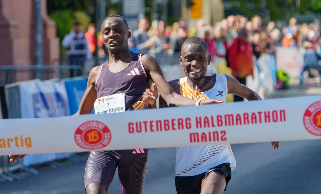 Im letzten Moment gleichauf: Victor Kiptoo (l, Uganda) und Benson Nzioki (Kenia) kommen beim Gutenberg-Halbmarathon in Mainz zur gleichen Zeit ins Ziel und teilen sich nach derzeitigem Stand den ersten Platz. - Foto: Andreas Arnold/dpa