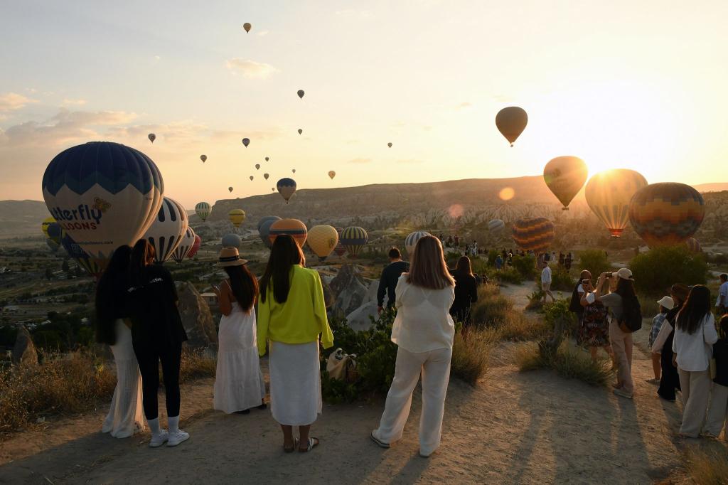 Zahlreiche Schaulustige bestaunen wie im türkischen Kappadokien Heißluftballons über Gesteinsformation Kappadokien fliegen. - Foto: Mustafa Kaya/XinHua/dpa