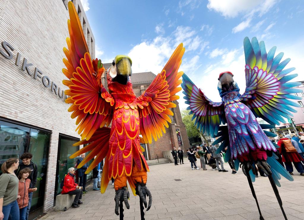 Zwei Papagei-Statuen stehen für die Eröffnungsparade des Figurentheaterfestivals Fidena in Bochum auf der Straße. Mit übergroßen Insekten und seltsamen Lebewesen wurde ein Statement gegen das Artensterben gesetzt. - Foto: Dieter Menne/dpa