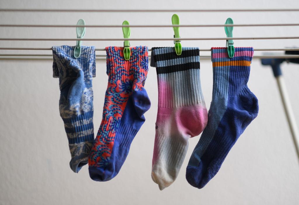 Bunte Socken hängen auf einem Wäscheständer. Am 9. Mai ist Tag der verschwundenen Socken. - Foto: Robert Michael/dpa