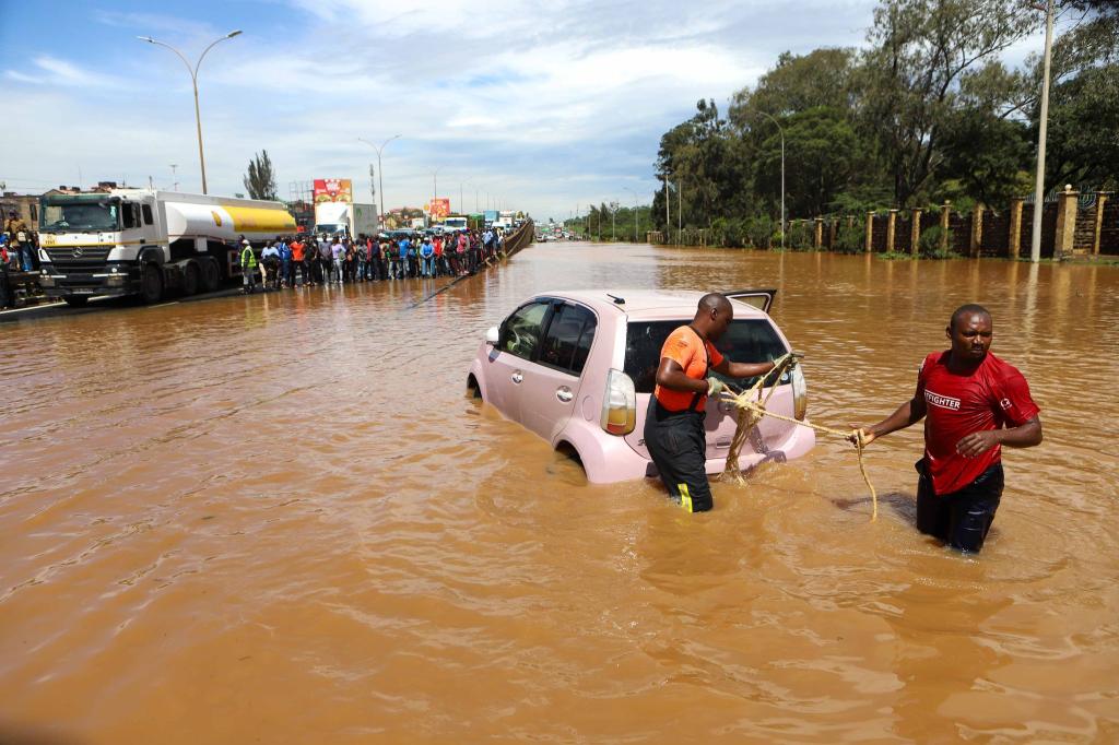 Menschen in Nairobi, die im Hochwasser ein Auto ziehen. - Foto: Joy Nabukewa/XinHua/dpa