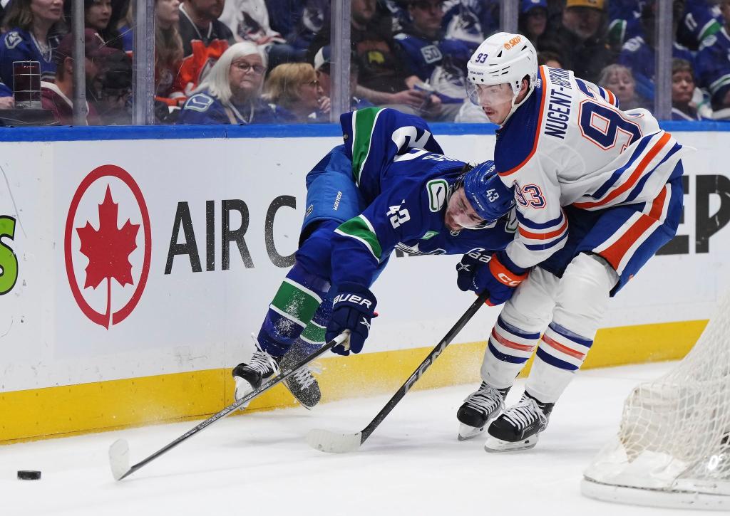 Quinn Hughes von den Vancouver Canucks wird von Ryan Nugent-Hopkins von den Edmonton Oilers zu Fall gebracht. - Foto: Darryl Dyck/The Canadian Press via AP/dpa