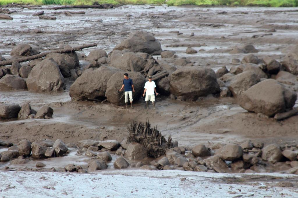 Menschen betrachten ein von einer Sturzflut betroffenes Gebiet in Indonesien. Schwere Regenfälle und Ströme kalter Lava und Schlamm haben Sturzfluten ausgelöst. Mehr als ein Dutzend Menschen wurden dabei getötet. - Foto: Ali Nayaka/AP/dpa