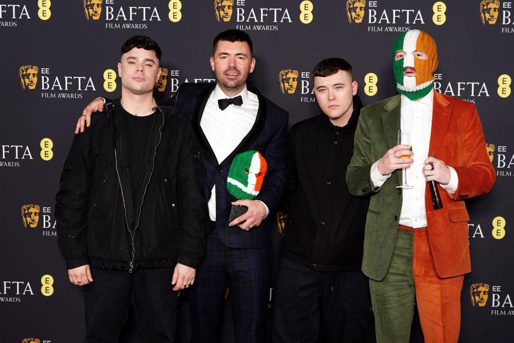 Die nun ins Visier von Ermittlungen geratene Band Kneecap wurde gemeinsam mit Regisseur und Autor Rich Peppiatt (Zweiter von links) bei den Bafta-Awards für einen gemeinsamen Film ausgezeichnet. - Foto: Ian West/PA Wire/dpa