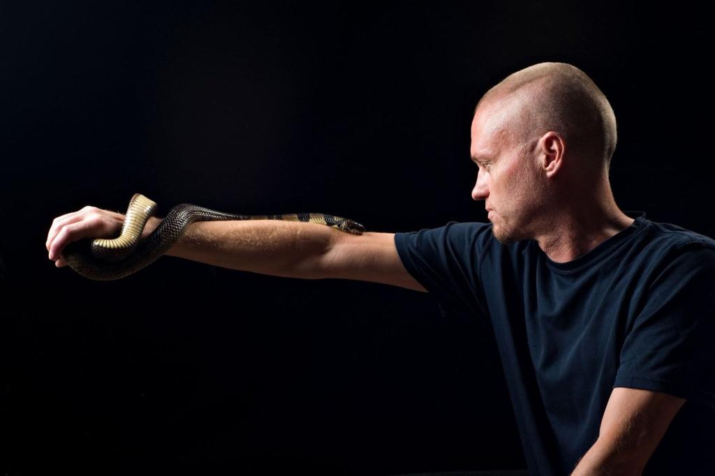 Der von Schlangen begeisterte US-Amerikaner Tim Friede hat sich selbst immer größere Dosierungen von Schlangengiften verabreicht und kann nun einfach so eine Wasserkobra auf dem Arm tragen. - Foto: ---/Centivax/dpa