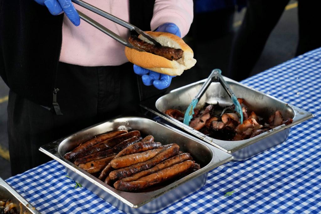 Ein Arbeiter bereitet in der Marrickville Public School in Sydney, Australien, eine "Demokratie-Wurst" für jemanden zu, der bei den Parlamentswahlen seine Stimme abgegeben hat. Der verführerische Duft brutzelnder Würstchen ist in Australien fester Bestandteil jeder Wahl. Traditionell steht vor vielen Wahllokalen ein Grill, an dem sich die Bürger mit einer Art Hot Dog (Bratwurst im weichen Brötchen mit Zwiebeln, Senf und Ketchup) stärken können: dem sogenannten «Democracy Sausage». - Foto: Rick Rycroft/AP/dpa