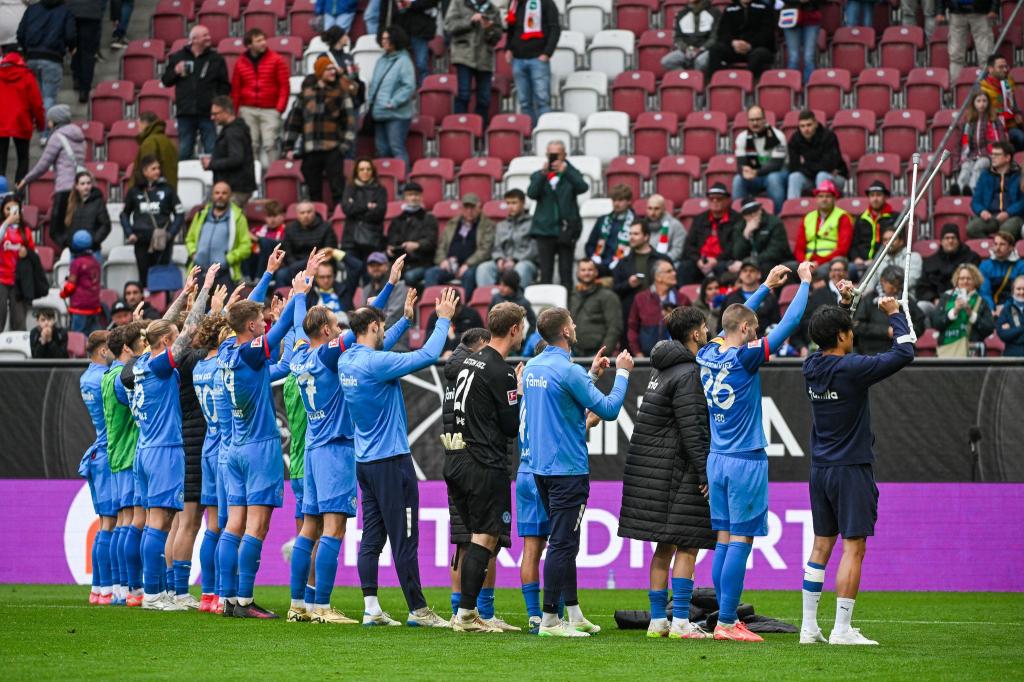 Holstein Kiel feiert den Sieg in Augsburg mit den mitgereisten Fans - Foto: Armin Weigel/dpa