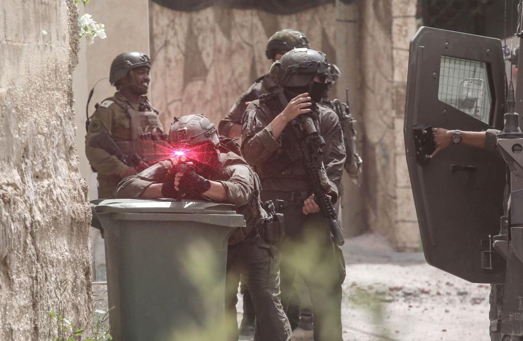 Israelische Soldaten gehen während einer Militäroperation im Norden des besetzten Westjordanlandes in Stellung. Ein Soldat zielt auf den Fotografen, man sieht die Laserzieleinrichtung leuchten. Die israelische Armee hat während einer Militäroperation in der Stadt Tamun ein Gebäude umstellt und fünf Palästinenser getötet, die sich darin verbarrikadiert hatten. - Foto: Nasser Ishtayeh/SOPA Images via ZUMA Press Wire/dpa