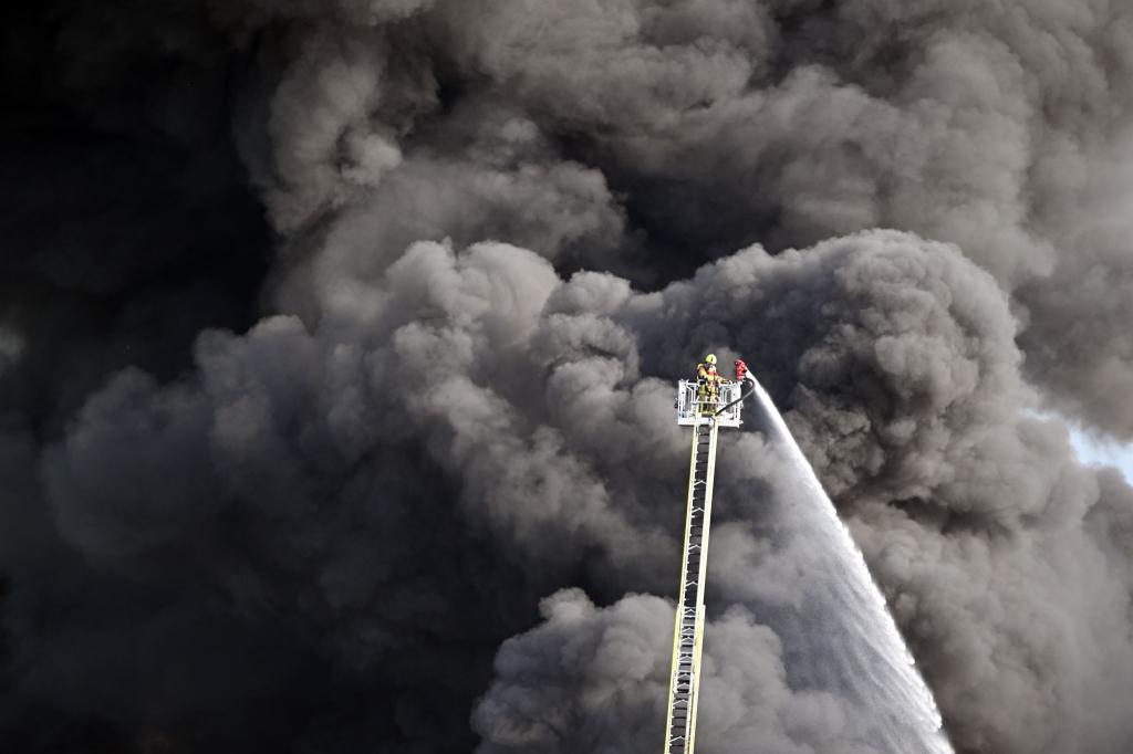 Kampf gegen das Feuer: Feuerwehrleute löschen den Brand einer Lagerhalle mit Müll in der Gemeinde Swisttal bei Bonn. - Foto: Federico Gambarini/dpa