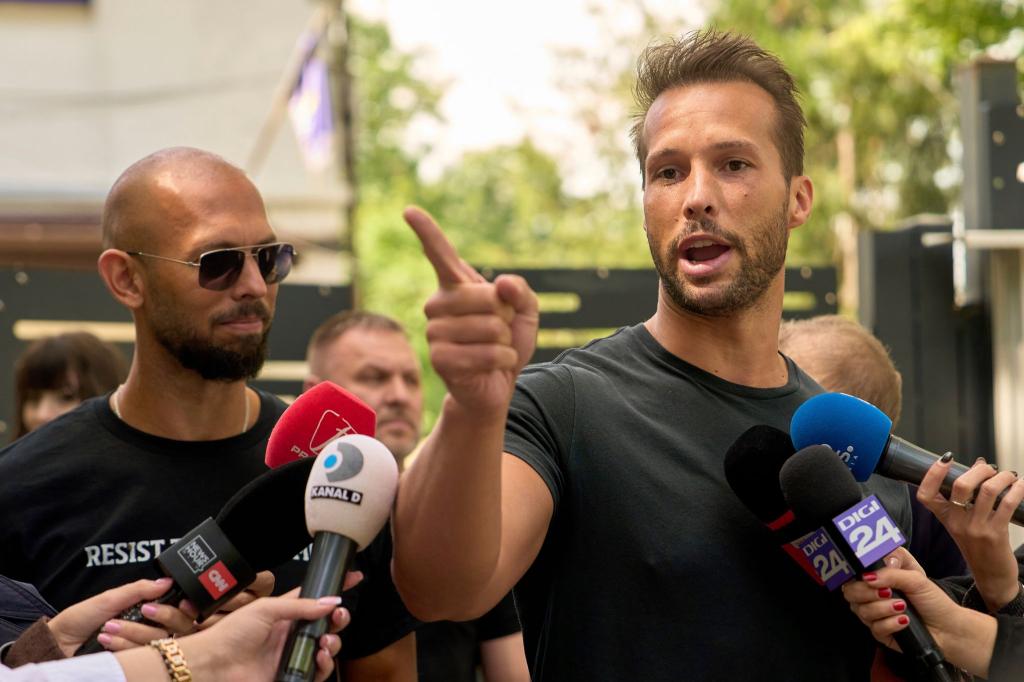 Andrew Tate (links) schaut zu seinem Bruder Tristan Tate, der am 21. Mai vor einer Polizeistation in Voluntari in Rumänien redete. - Foto: Vadim Ghirda/AP/dpa