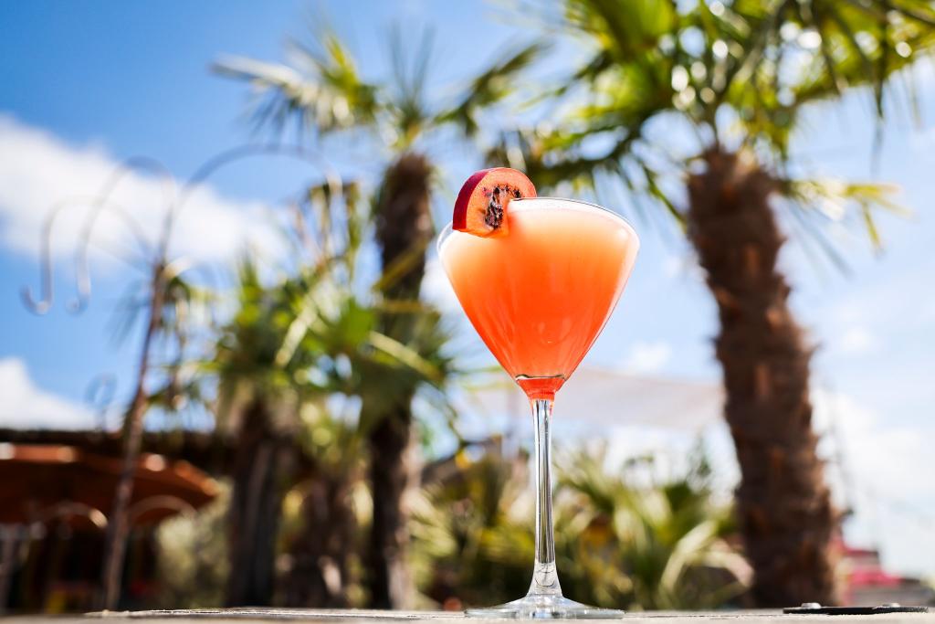 Ein Passionsfrucht Martini (auch Pornstar Martini oder Maverick Martini genannt) steht unter Palmen auf einem Tisch in einer Strandbar. - Foto: Christian Charisius/dpa