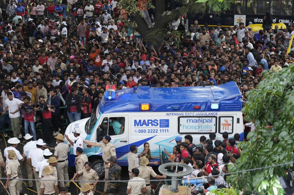 Ein Krankenwagen bahnt sich den Weg durch eine Menschenmenge am M. Chinnaswamy-Stadion in der indischen Stadt Bengaluru. - Foto: Aijaz Rahi/AP/dpa