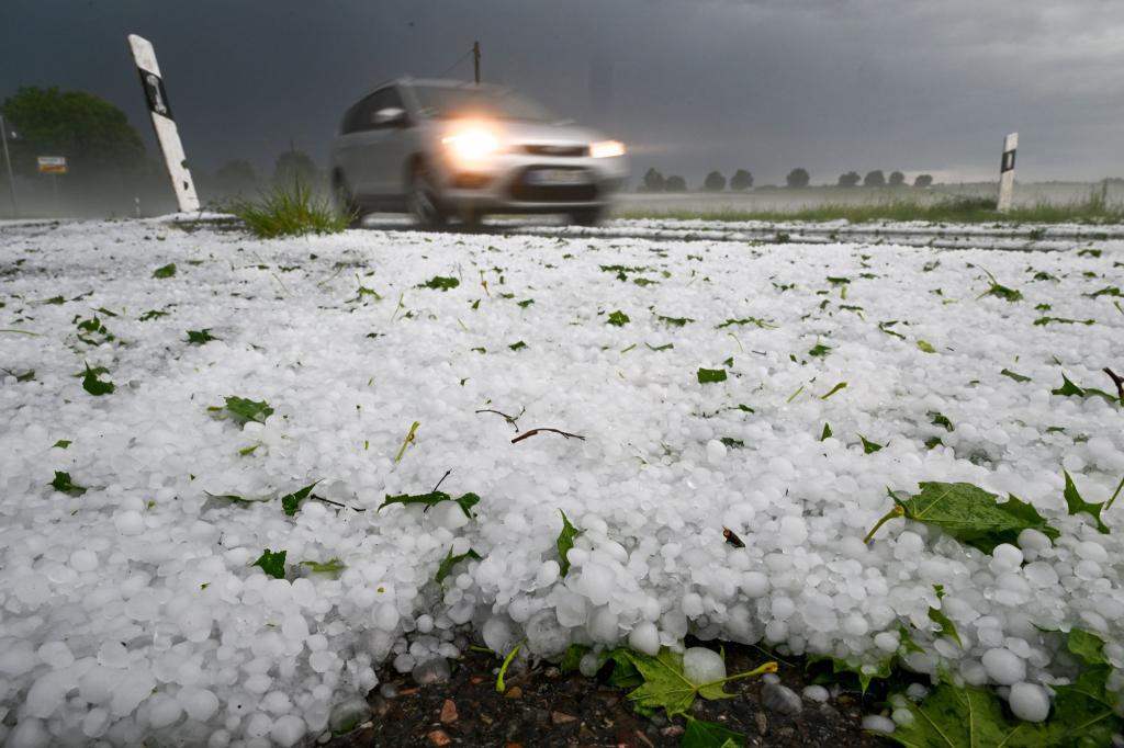 Hagel liegt auf der Straße. Ein Unwetter hatte sich zuvor in der Region um Laupheim mit Blitz und Hagel entladen. - Foto: Felix Kästle/dpa