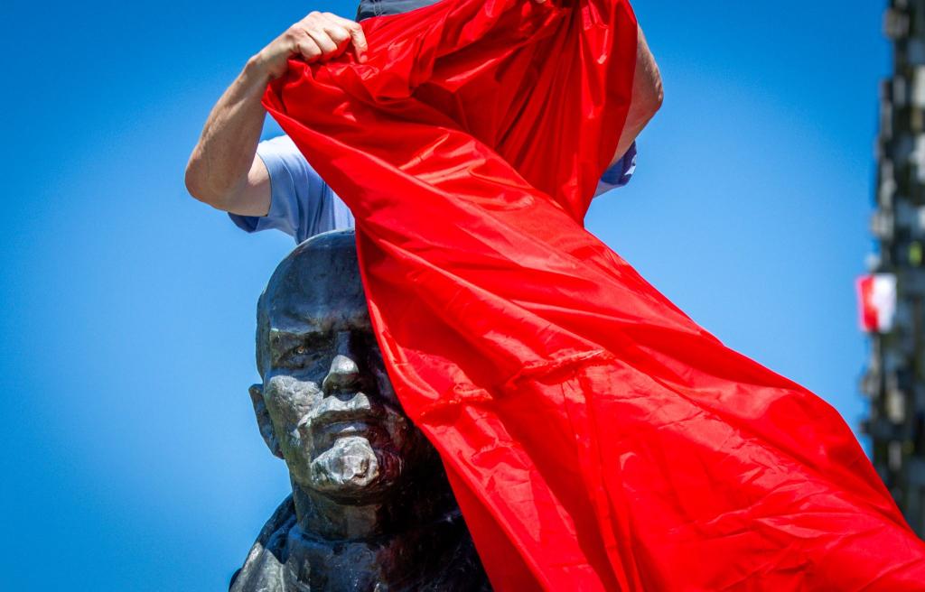 Vertreter von Opferverbänden verhüllen bei einer Kundgebung in Schwerin eines der letzten Lenin-Denkmäler in Deutschland und protestieren damit gegen die öffentlichen Ehrungen der Repräsentanten von Systemen der Gewaltherrschaft. - Foto: Jens Büttner/dpa