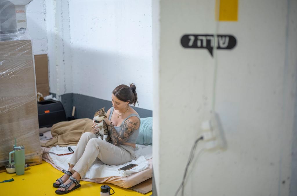 Zwischen Alltag und Alarm - Katze und Frau suchen während eines Raketenangriffs Zuflucht im Parkhaus - Foto: Ilia Yefimovich/dpa