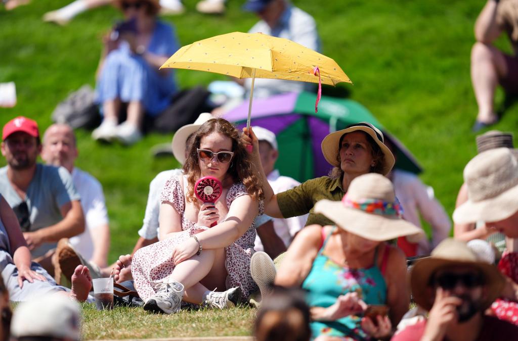 Zuschauer schützen sich gegen die Sonne und Hitze in Wimbledon. - Foto: John Walton/PA Wire/dpa