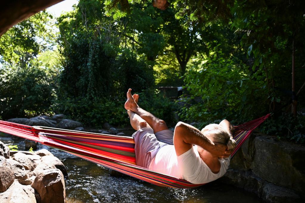 Ein Mann schaukelt im Berliner in einer Hängematte über dem Wasser. - Foto: Katharina Kausche/dpa