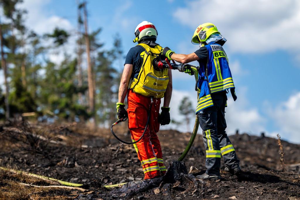 Mit Löschrucksäcken gehen die Feuerwehrleute etwa gegen Glutnester vor. - Foto: Jacob Schröter/dpa