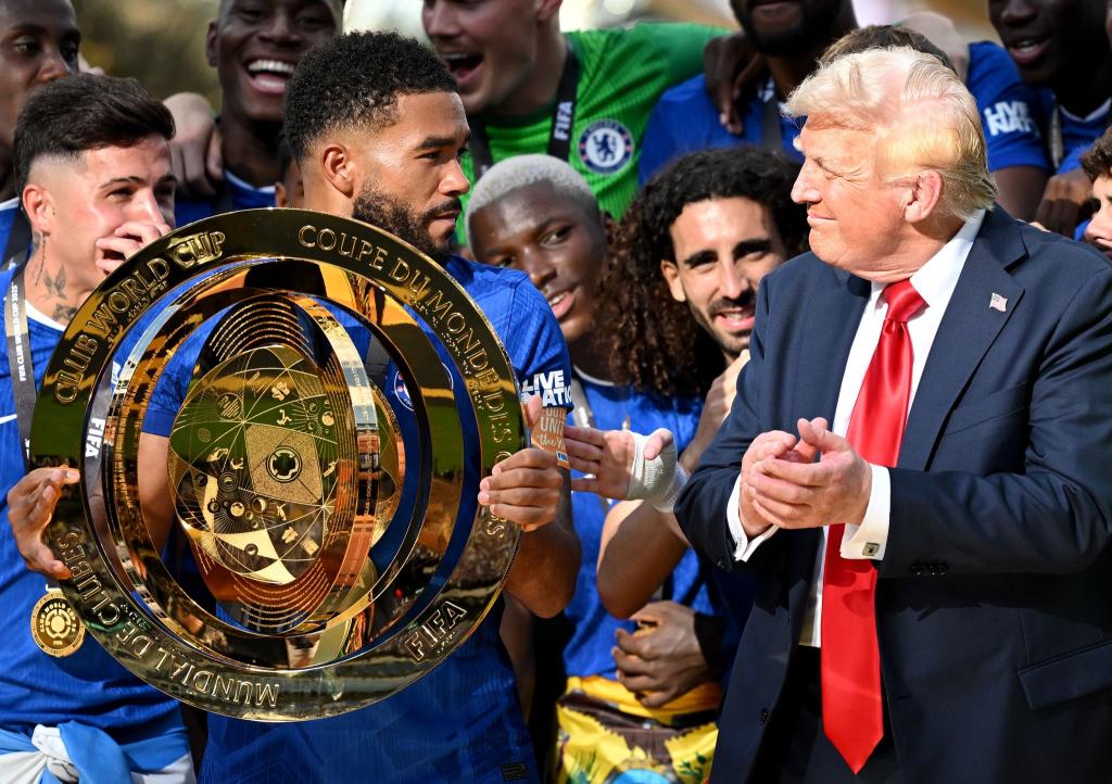 Chelseas Kapitän Reece James (l/vorn) hält auf dem Siegerpodest die Trophäe in den Händen und schaut irritiert zu US-Präsident Donald Trump. - Foto: Sven Hoppe/dpa