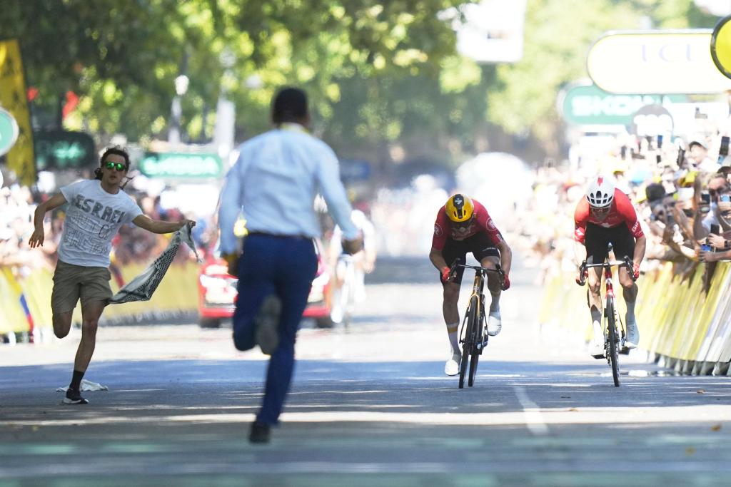 Während Jonas Abrahamsen und Mauro Schmid (r) in Toulouse um den Sieg sprinten, läuft ein Flitzer (l) auf die Zielgerade. - Foto: Thibault Camus/AP/dpa