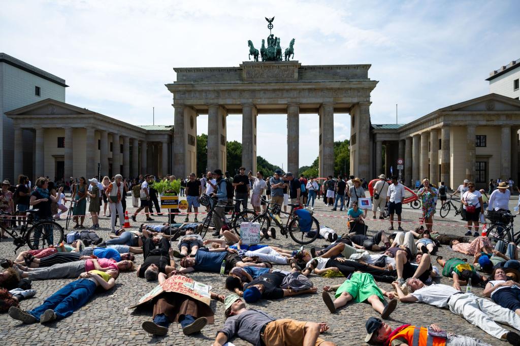 Teilnehmer einer Demonstration des Bündnisses "BaumEntscheid" liegen auf dem Boden auf dem Pariser Platz und simulieren einen Hitzetod. - Foto: Christophe Gateau/dpa