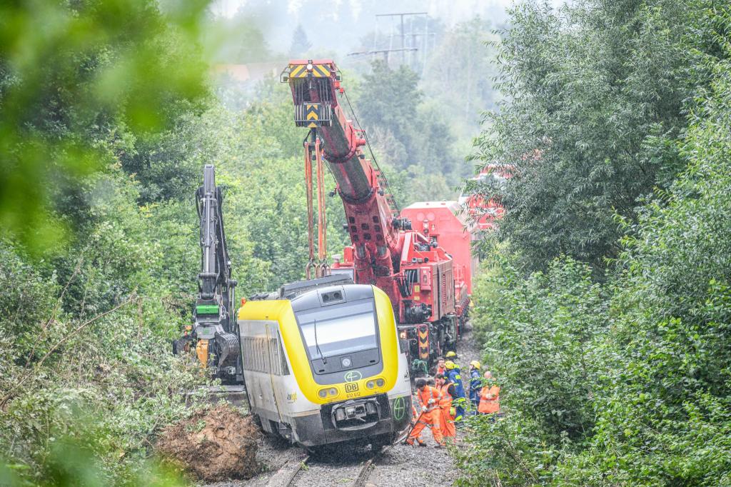 Mit einem Kran wird an der Unfallstelle, an der ein Regionalzug entgleist ist, gearbeitet. Ein Regionalexpress war am Sonntagabend (27.07.2025) in Riedlingen nach bisherigen Erkenntnissen infolge eines Hangrutsches entgleist. - Foto: Jason Tschepljakow/dpa