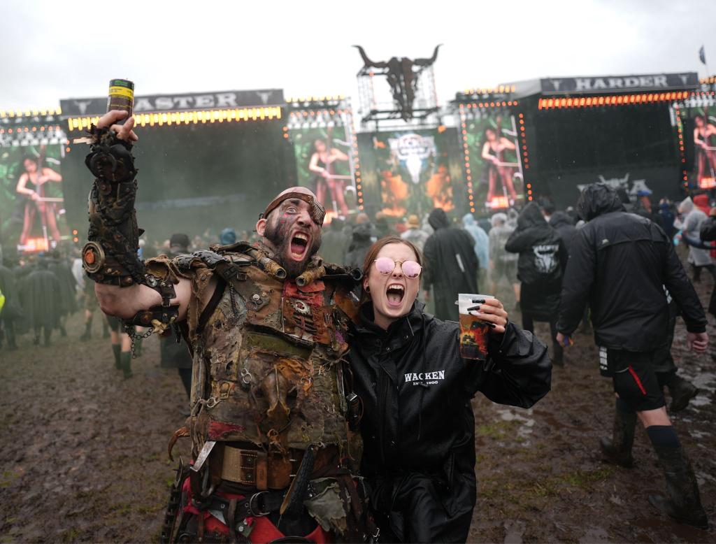 Metalfans feiern nach der Öffnung des sogenannten «Infield» vor den beiden Hauptbühnen auf dem Festivalgelände des Wacken Open Airs. - Foto: Marcus Brandt/dpa