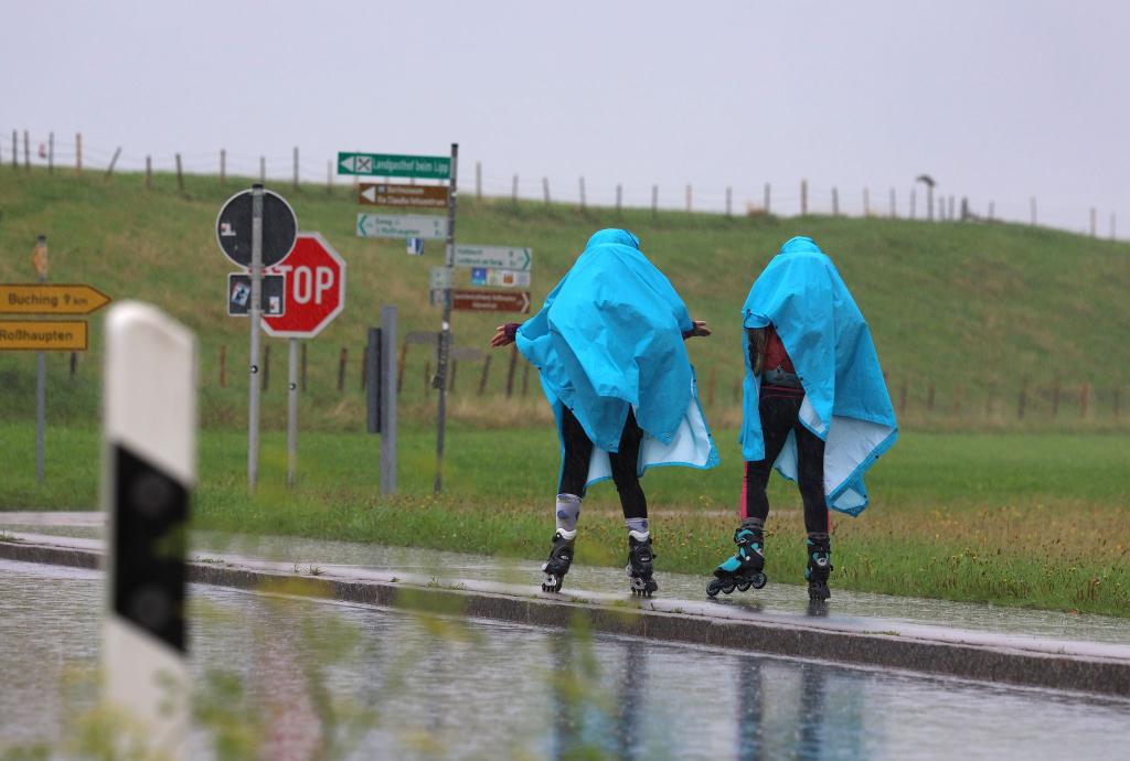 Alles eine Frage der richtigen Kleidung - Zwei Inline-Skaterinnen fahren im strömenden Regen im bayerischen Roßhaupten. - Foto: Karl-Josef Hildenbrand/dpa