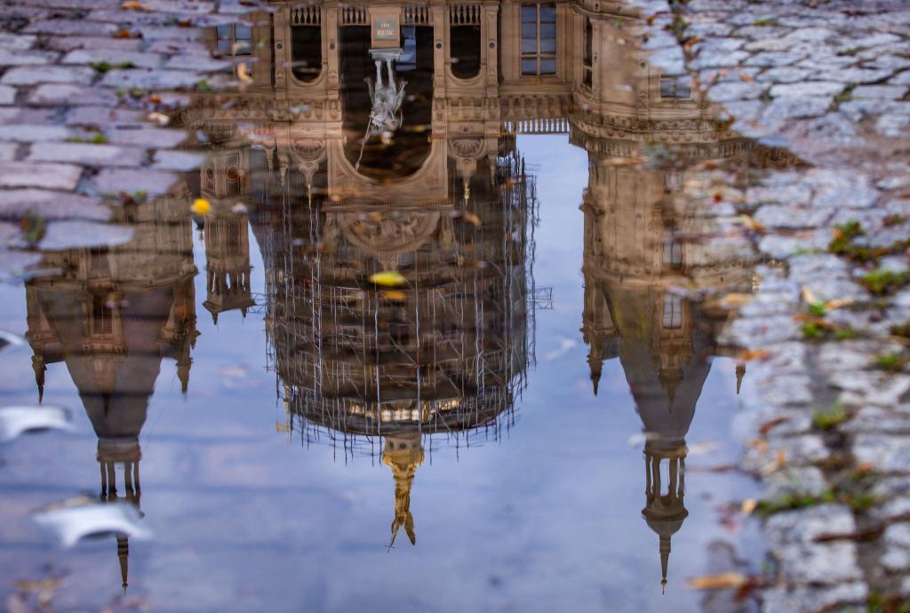 Das Schweriner Schloss spiegelt sich in einer Regenpfütze – graues, kühles und regnerisches Wetter zeigt den norddeutschen Sommer von seiner unfreundlichen Seite. - Foto: Jens Büttner/dpa