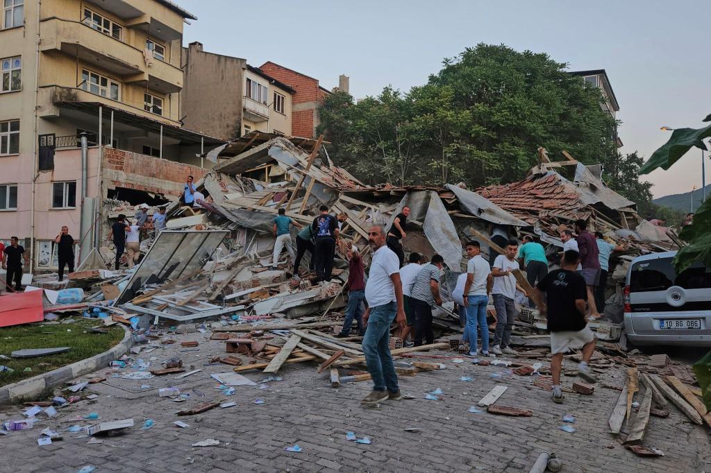 Menschen beseitigen in Sindirgi die Trümmer eines eingestürzten Gebäudes. - Foto: Bahadir Demirceviren/IHA/AP/dpa