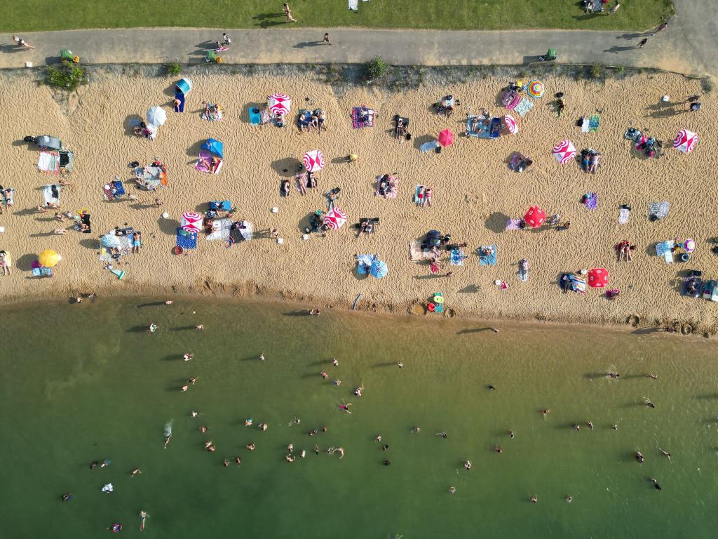 Badegäste liegen am Strand am Rather See in Köln (Luftaufnahmen mit einer Drohne). - Foto: Sascha Thelen/dpa
