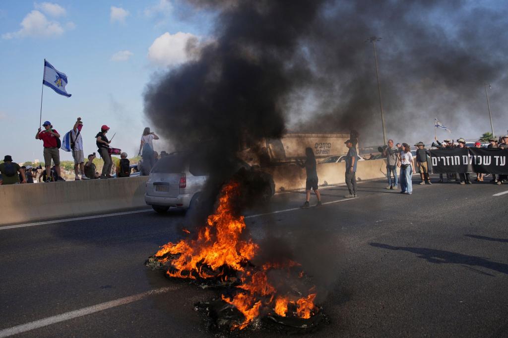 Israelische Demonstranten blockieren eine Straße bei einem Protest. - Foto: Ohad Zwigenberg/AP/dpa